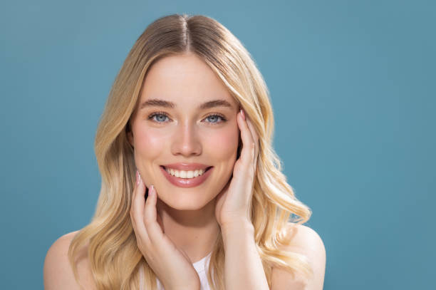 Smiling young woman with blonde hair on blue background