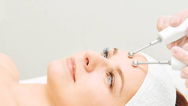 Woman receiving microcurrent facial treatment in spa