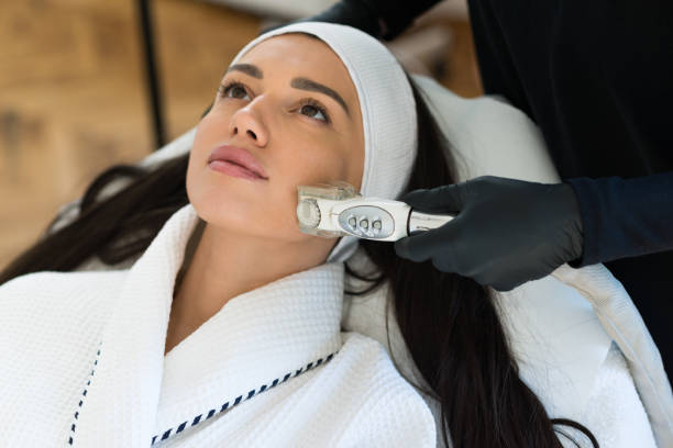 Woman receiving facial treatment with modern skincare device