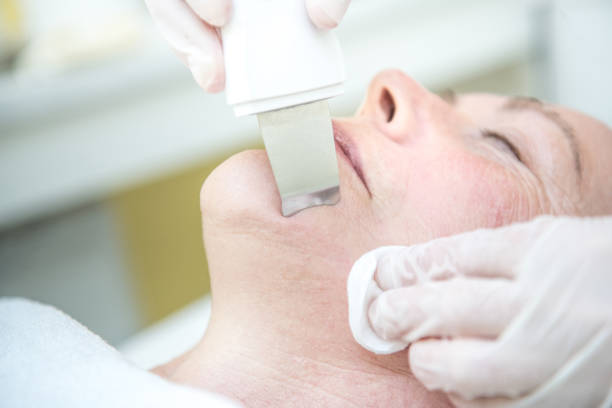 A woman receiving a facial treatment with an ultrasonic skin spatula, focusing on rejuvenation and cleansing of the neck area.